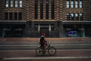 A woman rides her bicycle past the Amsterdam City Archives building, showcasing urban cycling culture.