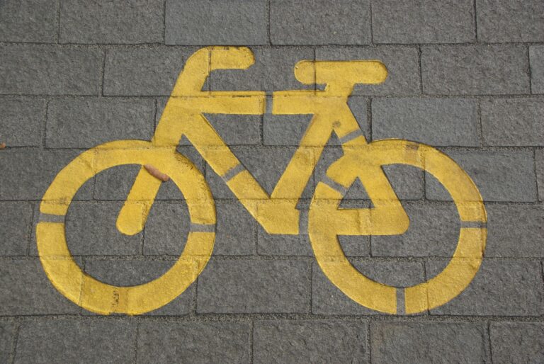 Bright yellow bicycle symbol on gray pavement marking a bike lane.
